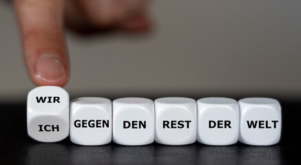 Hand turns dice and changes the German phrase 'Ich gegen den rest der Welt' (I against the rest of...