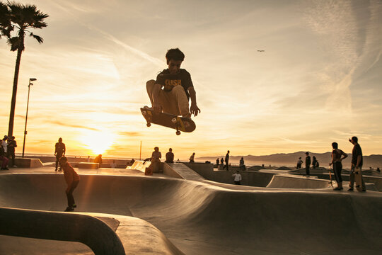Teenage boy skating at skatepark during sunset