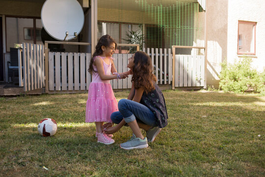 Girl tying her sister's shoe in backyard