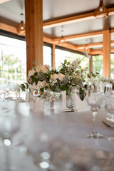 Table centerpiece with white and green floral arrangement in vase.