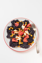 Fresh salad with curly cabbage or kale, grapefruit, feta or tofu and chickpeas topped with sause and sesame seeds in plate with fork isolated on white top view
