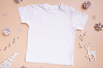 Baby t-shirt mockup for logo, text or design on beige background with winter decotarions top view.
