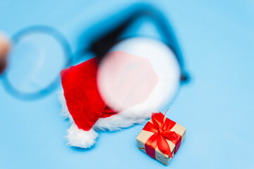 Santa Claus hat, a Christmas gift tied with a red ribbon through round Santa Claus glasses. Selective focus. blur in glasses