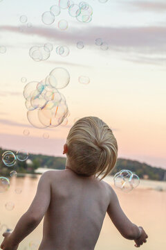 Boy playing with bubbles at sunset