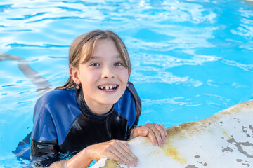 Portrait of happy smiling girl in the swimming pool with copy space.