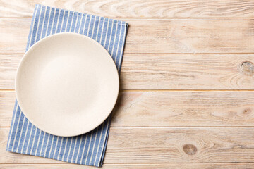Top view on colored background empty round white plate on tablecloth for food. Empty dish on napkin with space for your design