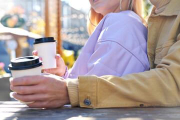 Young man enjoying coffee to go and hugging a beautiful woman from behind