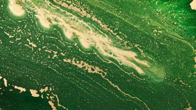 4k video gold shine in green bright liquid texture background. Golden shining stripe in green ink art. Emerald wet watercolor backdrop. Slow motion. Bright green paint pattern. Acrylic vertical video