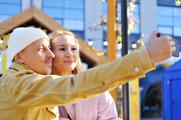 Obraz premium A couple in love, a guy and a girl, take a selfie together in sunny weather. couple looking at camera and smiling