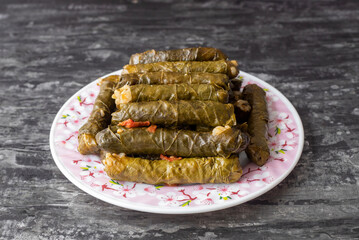 Delicious dolma (sarma) stuffed grape leaves rice, white yogurt sauce. Lebanese dolma sarma on plate. Lebanon turkish greek middle eastern cuisine. (Turkish name; Yaprak sarma)
