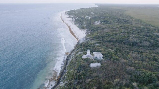 Aerial dolly drone shot of the coast in Tulum Mexico with rocks, sandy beach  with view to the cloudy sky sunrise 4K