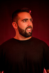 Portrait of a young man with beard on a red and black background with smoke.