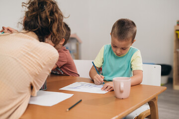 Fototapeta premium Young boy drawing in preschool
