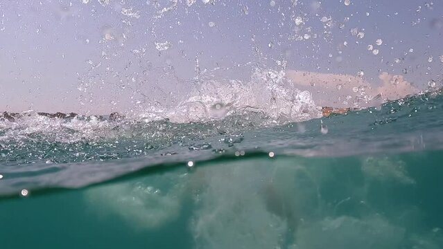 Half underwater back view scene of little redhead girl diving in clear blue water. Slow motion close-up