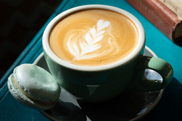 Cappuccino with blue macaron on the blue green table