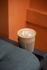 Paper cup with cappuccino on the bench