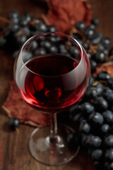 Red wine and blue grapes on an old wooden table.