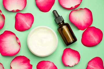 Skin care products, natural cosmetics. A flat image on a green background of a bottle of natural cosmetics for skin care, serum and rose petals.
