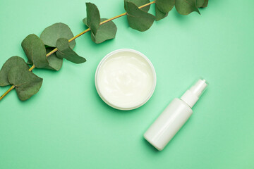 Organic cosmetic products with green leaves on color background. Copy space, flat lay.