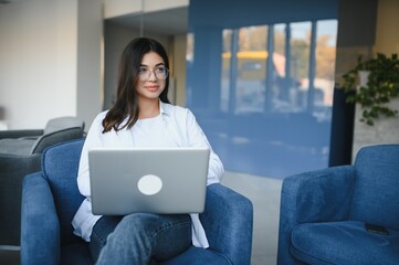 Joyful girl student studying online at cafe, using laptop and earphones, empty space