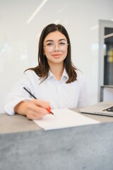 friendly young woman behind the reception desk administrator