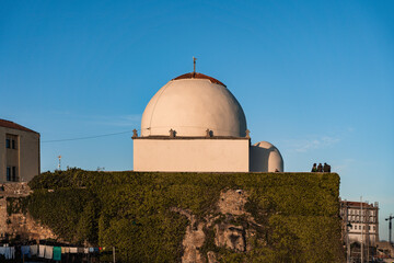 Um predio com uma copula redonda banhado pelo sol, ao por do sol