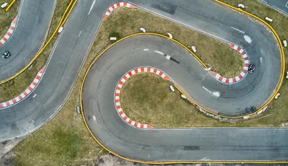 Deurstickers Aerial top view of the go-kart track from the drone. Kart racers drive on the open track. © rjankovsky