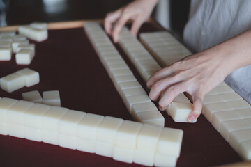Hands arranging, playing Mahjong game. Concept of chinese leisure games traditional, family activity, Hongkong board game, chinese new year fmily time entertainment. Lucky game.