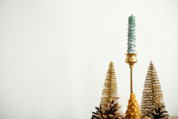 Christmas table decor. Stylish christmas golden trees, golden candles against white wall. Modern...