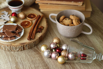 Cup of tea or coffee, various sweets and spices, Christmas decorations, comfy blanket, books and glasses. Selective focus.