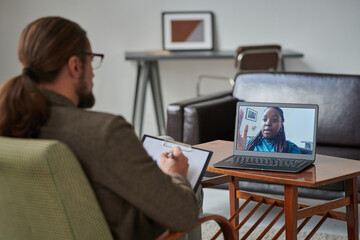 African American young girl talking to psychologist online, she discussing problems while he making notes in card - obrazy, fototapety, plakaty