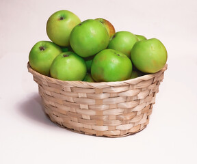 Green apples in a wicker basket on a white background