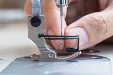 Sewing machine and thread rolling. Man hand work needles thread
