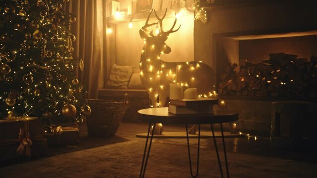 Christmas and New Year interior decoration. Green tree decorated with toys, gifts, present boxes, flashing garland, illuminated lamps. Fireplace with burning fire. Cozy Christmas atmosphere. 4K