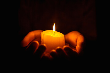 Burning candles in the boy hands on a dark background.Religious concept.