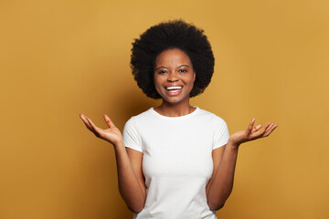 Happy young woman wearing white t-shirt having fun against bright yellow studio wall banner...