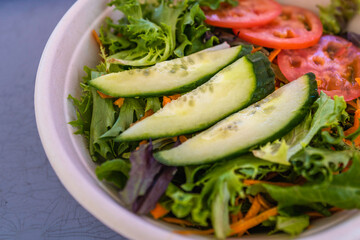 Salad with cucumber, tomatoes, lettuce, and onion with Italian dressing, takeout food close-up