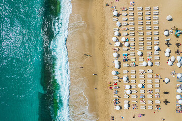 Fototapeta na wymiar aerial shooting from a drone on a sandy beach with people sunbathing and relaxing. Flat view of the shore and turquoise waves of the surf and people bathing