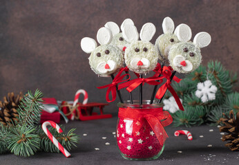 Cute idea for Christmas treats - cake pops Rabbits made from cookies in chocolate, coconut flakes and marshmallows on brown background