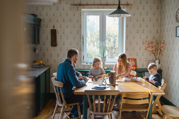 Happy young family at dining table at home together 
