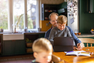 Fototapeta na wymiar Dad using tablet at home with kids 