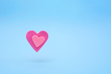 Fototapeta na wymiar Floating soft pink hearts made of vivid air plasticine, a colorful air mass for children's art on pastel buel background. Expression of love, Valentine's Day.
