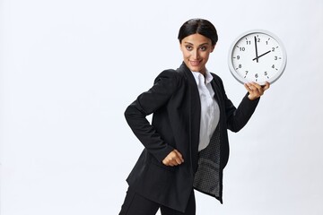 Business woman holding a wall clock in a black business suit and glasses showing signals gestures...