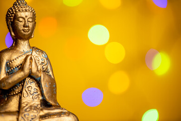 a golden buddha statue against a colored background - obrazy, fototapety, plakaty