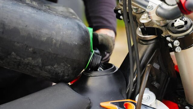 Man's Hands Pouring Petrol in Motocross Motorcycle Tank - close up slow motion. Man Fill the Tank with Fuel