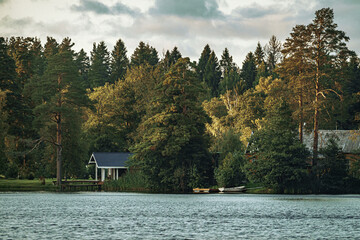 Recreation center on the lake shore in the forest. A great place for fishing in summer. Forest lake. Karelian landscape with boats. - obrazy, fototapety, plakaty