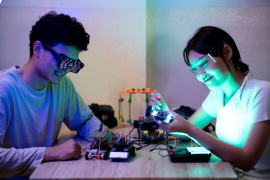 Young man and young woman amateur inventor testing electronic device model