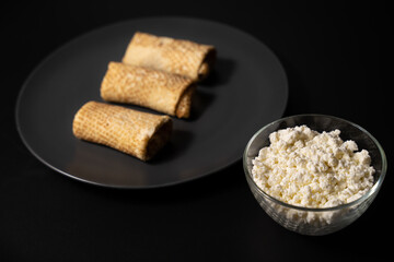 pancakes with cheese on a plate and kitchen utensils on a black background