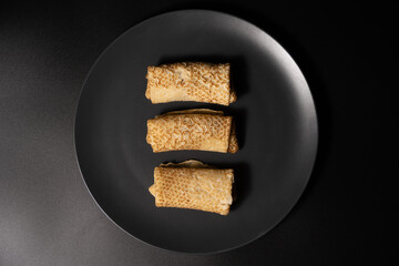 pancakes with cheese on a plate and kitchen utensils on a black background