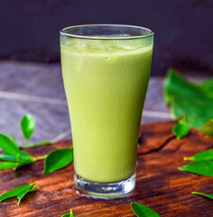 iced matcha latte, green tea with milk in a  glass with ice on wooden